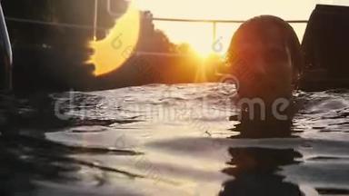 年轻的帅哥在美丽的夕阳下在游泳池里放松。 慢动作。 1920x1080